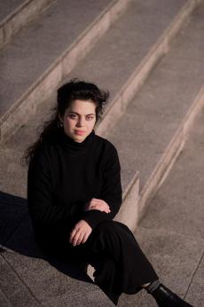 Une femme dans une chemise noire et un pantalon noir assise sur des marches
