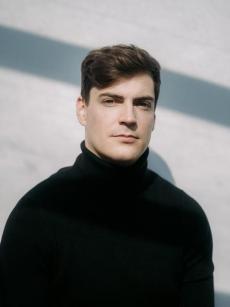 Un homme ux cheveux courts et portant une chemise noire