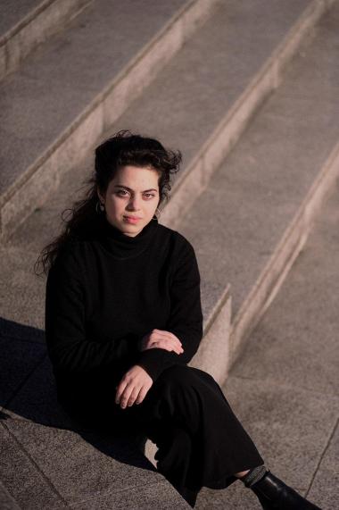 Une femme dans une chemise noire et un pantalon noir assise sur des marches