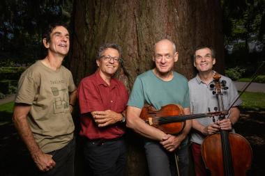 Photo des membres du quatuor qui posent devant un arbre avec leur instruments.