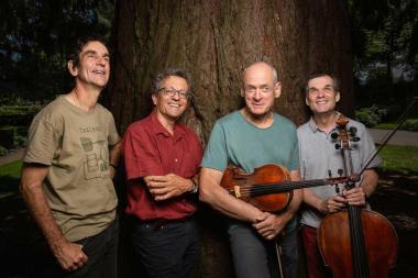 L'image montre le quatuor devant un grand arbre.