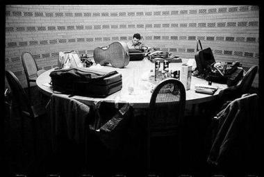Photo noir et blanc d'une table avec du matériel musical et un homme assis