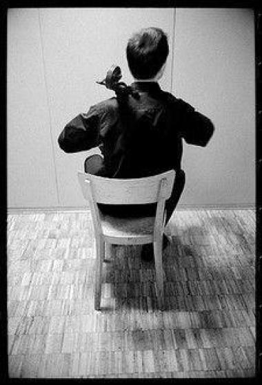 Photo noir et blanc d'un homme de dos assis sur une chaise qui joue d'un instrument